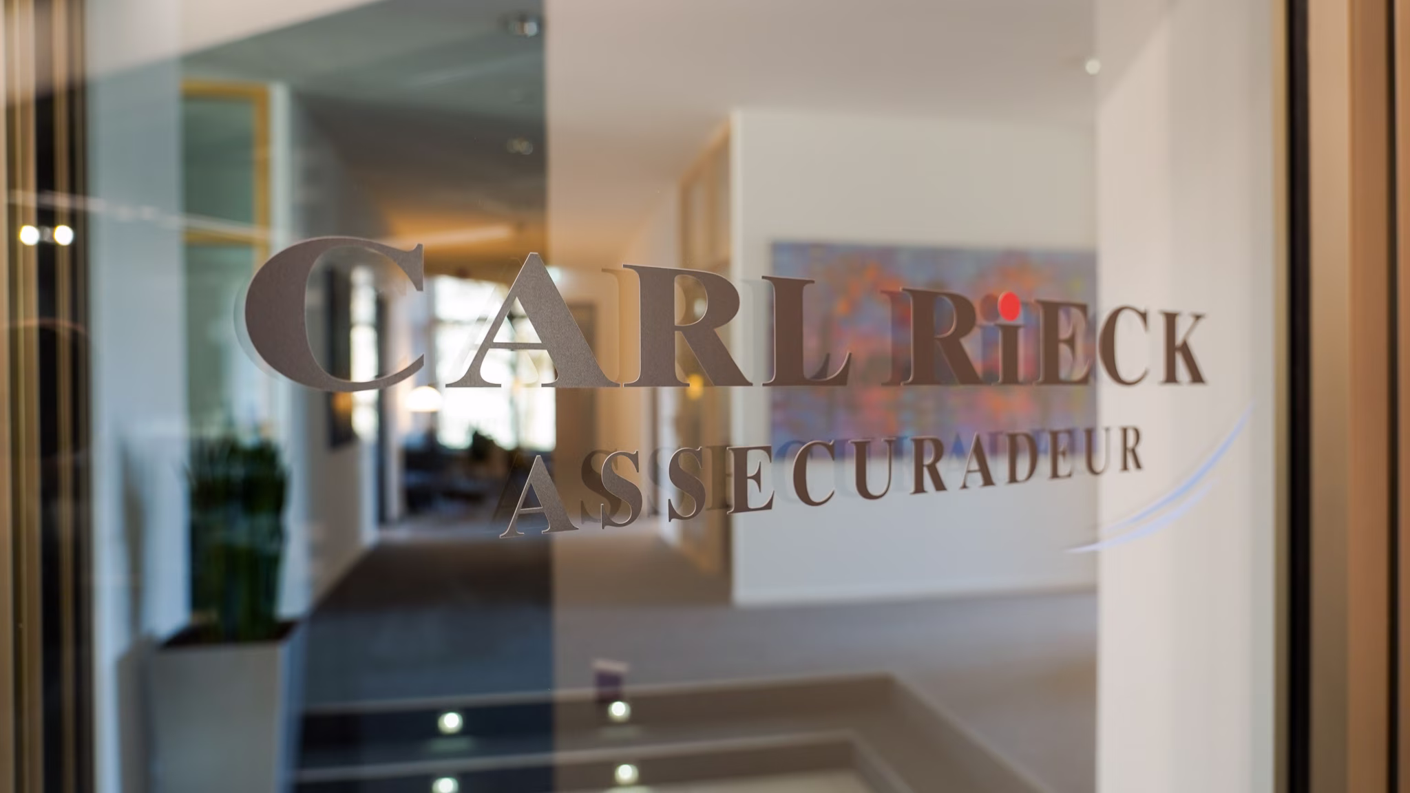 Das Logo von Carl Rieck Assecuradeur in Düsseldorf klebt am Eingangsbereich an der Tür.